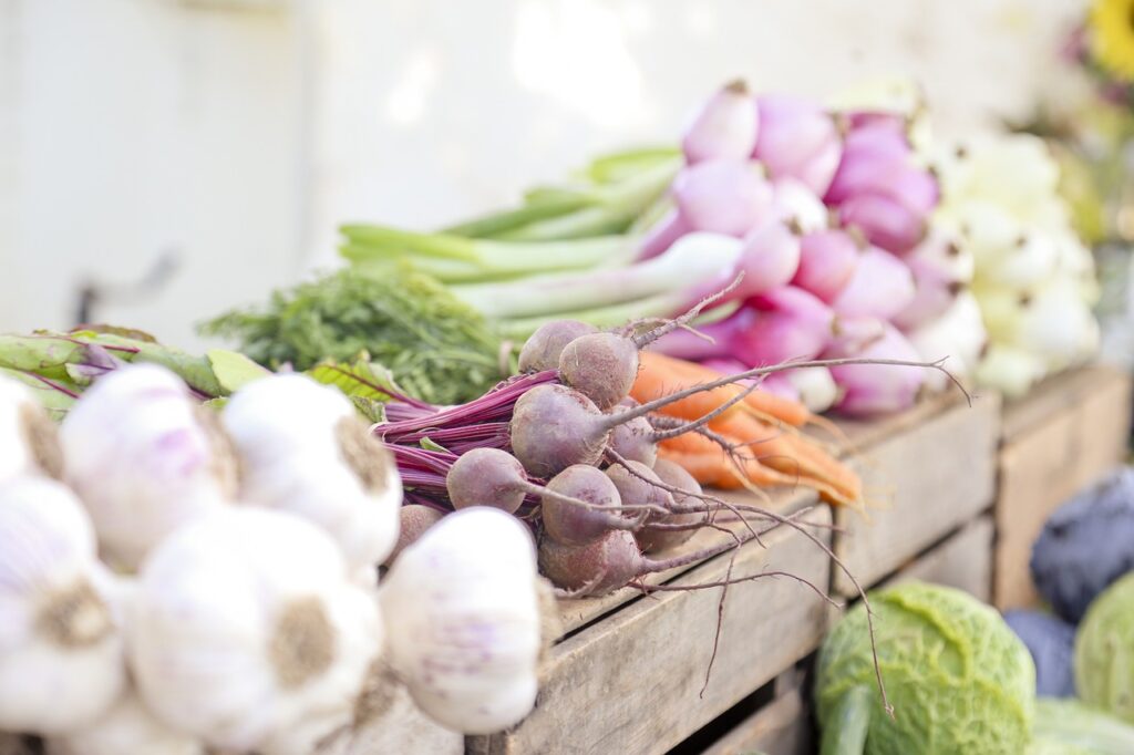 Beets, garlic, and onions displayed at market—crops often used in companion planting to protect each other and boost vegetable yields.