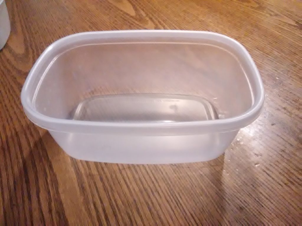 Clean deli meat container repurposed as a microgreen growing tray