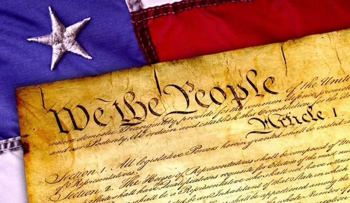 Historic parchment of the U.S. Constitution beside the American flag – symbol of freedom and liberty